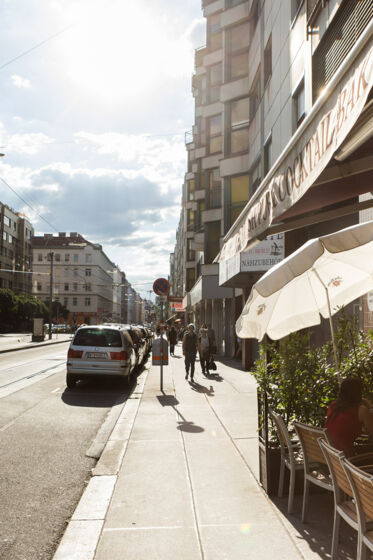 Straßenbahngleise, Straße mit Autos, Sonnenschirm Straße mit Café